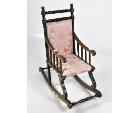 An Edwardian wooden bobbin turned child's rocking chair armchair, with pink floral upholstery
