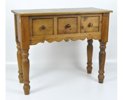 A 20th century pine side table, fitted with three drawers, raised on turned supports, 76cm x 90cm x 41cm