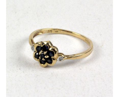 A ladies 9ct gold daisy cluster dress ring, with six blue stones forming the central cluster, flanked by one single white sto