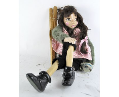 A Pelham type puppet of a girl with dark plaited hair, resin head, hands and boots, sticks with hand-written name 'Kaufmann' 