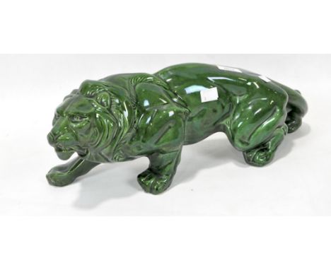 A ceramic model of a hunting lion, glazed in green, length 447cm.