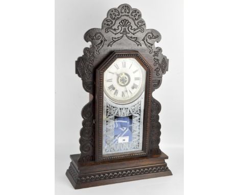 A vintage Ansonia USA clock, the white face displaying Roman numerals, in a carved wooden case with a reverse painted design 