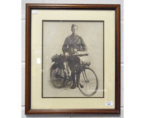 A WWI print of a dispatch rider with bicycle, 39cm x 31cm, framed and glazed