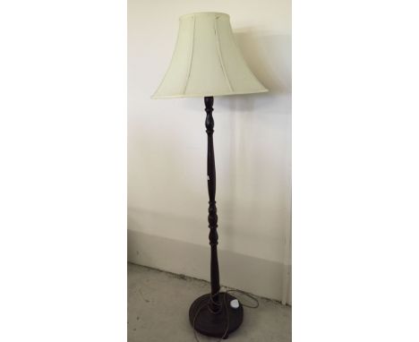 A dark wood standard lamp with cream shade.