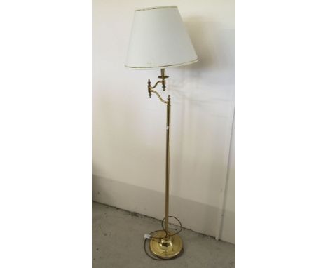 A brass standard lamp with cream shade.