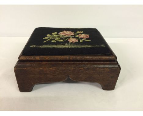A small dark oak foot stool with tapestry top