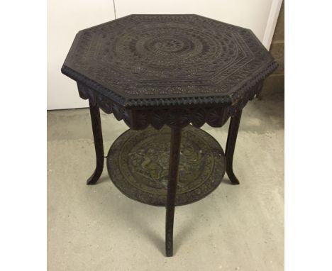 A ornately carved hexagonal occasional table with brass tray shelf.