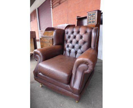 A chestnut brown leather button back armchair 