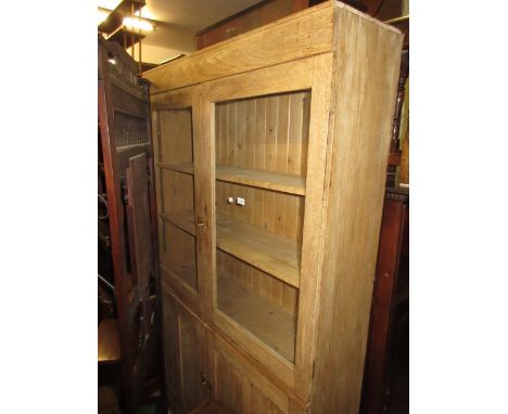 Stripped light oak bookcase with two glazed doors enclosing shelves above a pair of panel doors and plinth base