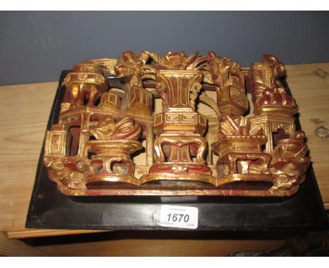 Chinese carved and gilded wall plaque depicting implements on a table with a central vase etc