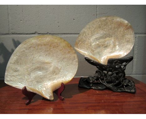 Two mother-of-pearl shells carved in relief depicting battle scenes, with stands