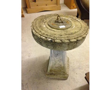 A concrete garden sundial with bird and ivy decoration - weathered