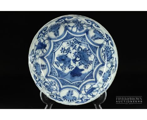 A Chinese blue & white porcelain saucer dish, painted with a central reserve of flowering trees and rockwork encircled by res