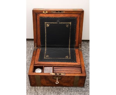 A walnut writing slope, brass inlay, the lid opening to reveal blue leather writing surface, pen compartment, and original gl