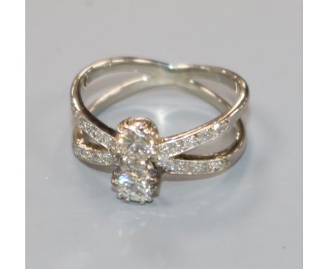 A white metal and two stone diamond set split shank ring, with diamond set shoulders, size K.