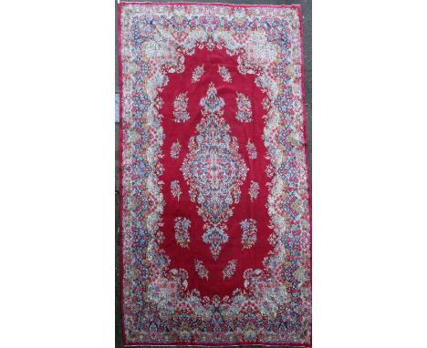 A North West Persian red ground carpet, with central foliate medallion surrounded with smaller floral motifs and extensive fl