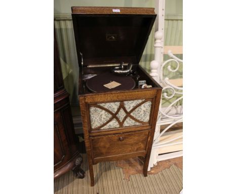 An oak cased His Masters Voice branded wind-up gramophone with internal speaker and a selection of 78 rpm records and needles