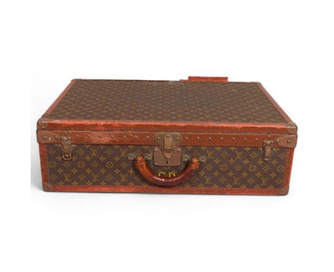 LOUIS VUITTON - a hard suitcase/trunk with monogrammed fabric, leather edging and brass corner mounts and locks, brass mounts