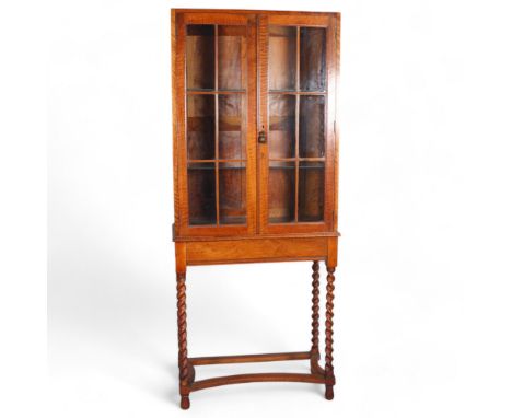 A Cotswold School English walnut and glazed display cabinet on fine barley twist legs with a cast bronze handle in the form o