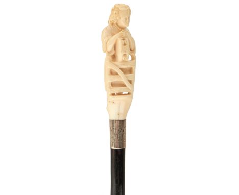 A 19TH CENTURY WALKING CANE, the ivory handle carved as a lady holding a tambourine and standing at a gate, white metal colla