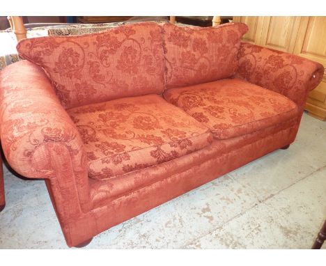 Pair of low backed red sofas comprising of large two seat sofa and matching smaller two seat sofa 