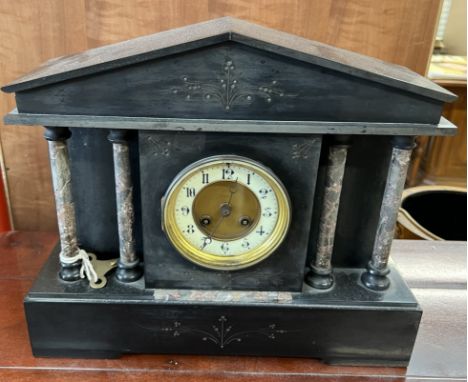 A black slate mantle clock of architectural form, with a circular dial and Arabic numerals