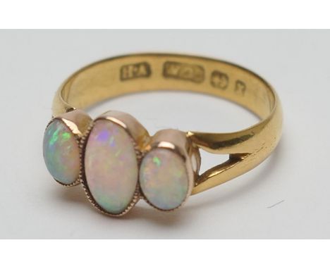 Opal three stone ring, the cabochon opals in beaded collet mounts, later worked on a Victorian 22ct gold wedding ring, size M