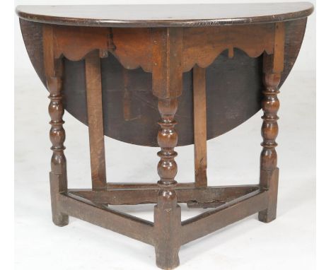 Oak joined credence table, demi-lune form with a single drop leaf, on a triform base with a single gate, turned and ringed le