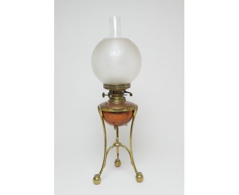 In the manner of W.A.S. Benson, brass and copper oil lamp, with a frosted spherical shade, copper tank over a brass tri-form 