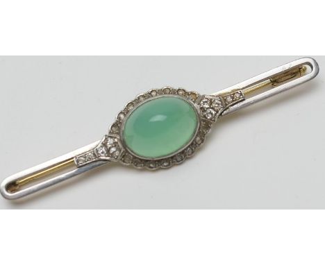Jade and diamond bar brooch, the celadon green cabochon bordered with rose cut diamonds set in white gold against a yellow go