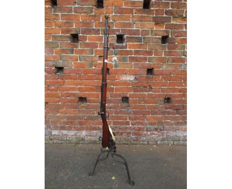 A vintage flintlock rifle converted to a standard lamp with bent wrought iron base