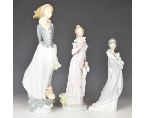 Three Lladro and Nao figures comprising Lladro girl holding book behind her, height 36cm, Lladro lady in shawl and Nao lady w