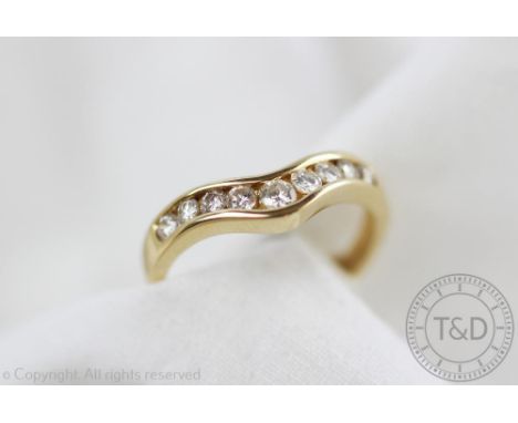 A diamond set ring, of shaped form and set with nine graduated brilliant cut diamonds, all set in yellow metal stamped '14K',