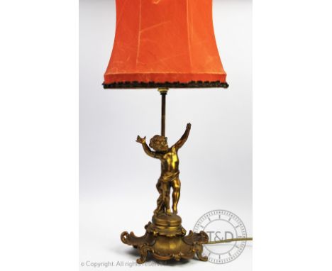 A Victorian gilt brass figural table lamp, modelled as a cherub standing upon a scroll base, 33cm high (excluding shade)    C