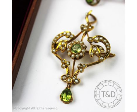 A late 19th/early 20th century peridot and seed pearl set pendant and brooch, of typical sinuous form and set with a central 