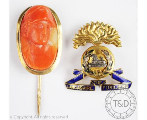 The Lancashire Fusiliers badge in yellow metal, unmarked, and a coral cameo stick pin, gross weight 9.4gms