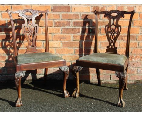 A pair of Chippendale style carved mahogany dining chairs, with elaboratley carved back and pierced splats above a drop in up