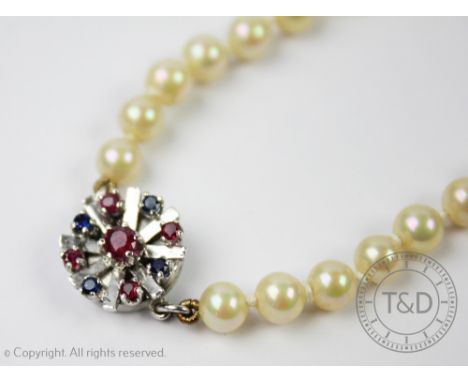 A cultured pearl necklace with gem set white metal clasp, the single strand of graduated cultured pearls, set to a circular c