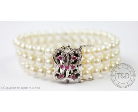 A cultured pearl bracelet with ruby set clasp, the three row cultured pearl bracelet attached to a rectangular white gold cla
