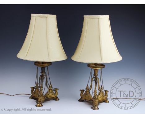 A pair of Victorian gilt metal Egyptian revival lamp bases, each of tri-form and modelled with three recumbent camels, 27cm h
