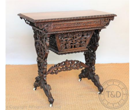 A late 19th century Burmese carved hard wood work table, rectangular top with writing drawer and silks drawer, on carved and 