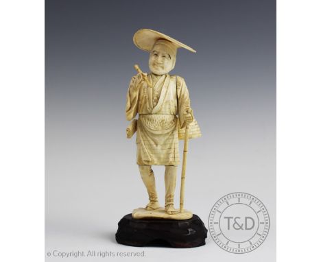 A Japanese carved ivory okimono, Meiji period (1868-1912),  modelled as a man standing supported by a cane and smoking an opi