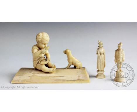 A late 19th/early 20th century European carved ivory group depicting a young boy eating with a dog by his side, on a raised p