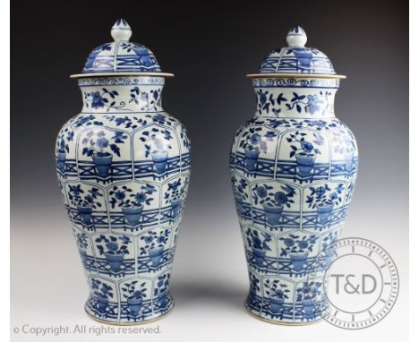 A large pair of Chinese blue and white baluster vases and covers, decorated with reserves and panels of blooms in a vase, fin