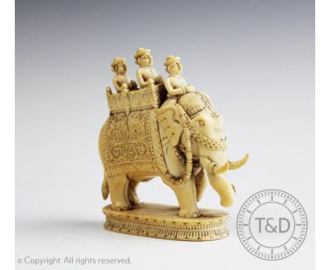 A 19th century carved ivory model of a caparisoned Indian elephant, modelled standing and carrying three attendants, 9cm high