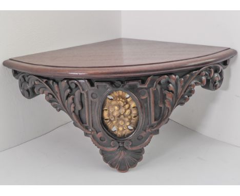 A nice quality quadrant-shaped mahogany wall bracket/shelf; thumbnail-moulded top above a central carved giltwood oval decora