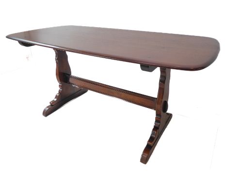 An Ercol oak dining table raised on shaped supports (152cm long x 76cm wide x 72cm high)