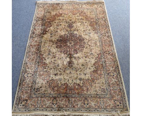 1 A modern wool Kashmiri carpet with central round floral medallion against a light-coloured ground, the border with varying 
