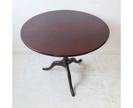 A George III period circular tilt-top mahogany occasional table: turned stem and on tripod base with elongated pad-style feet