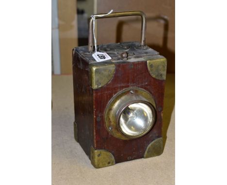 AN EARLY 20TH CENTURY WOODEN CASED LAMP, fitted for a 9 volt battery, with brass mounts, carrying handle to top, contains ref